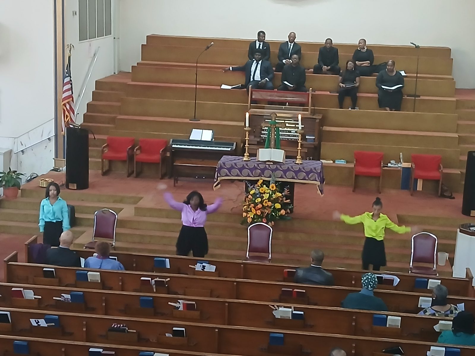 Three dancers at the front of the sanctuary during worship, with the choir seated in the loft behind them