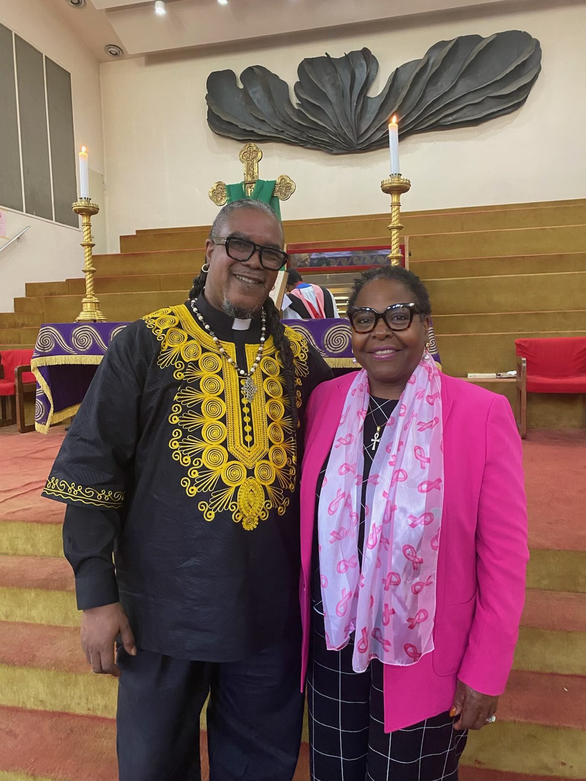 Rev. Eric A. Thomas and Assembly Member Stefani Zinerman smiling together in front of the chancel after the service